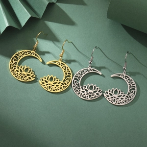 Macro detail of crescent moon and lotus earrings in gold and silver finish on green backdrop