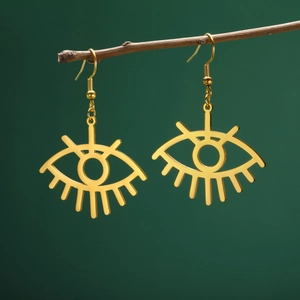 Macro view of gold stainless steel evil eye earrings hanging on a natural wood branch