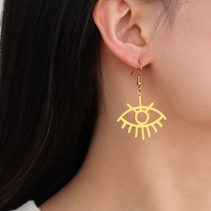 Detailed close-up of a gold stainless steel evil eye drop earring worn by a model