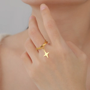 Dettaglio di un anello d'oro minimalista con ciondolo a stella e dettaglio catena fine