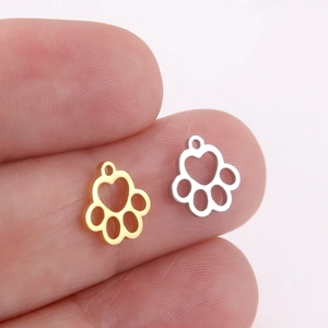 Gros plan de breloques patte de chat or et argent sur un doigt pour bijoux DIY