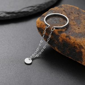 Dettaglio anello minimalista in argento con nappa a catena stellata e ciondolo tondo