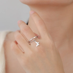 Dettaglio dell'anello con farfalla d'argento e catena pendente sulla mano della modella