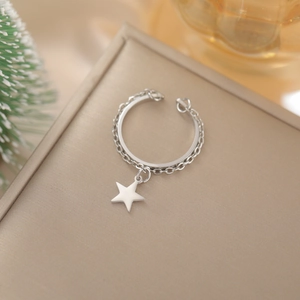 Dettaglio di un anello regolabile argento con ciondolo a stella e catena in metallo fine