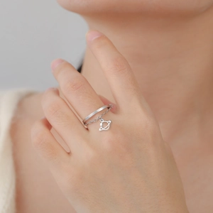 Dettaglio macro di un ciondolo a pianeta argento e catena su un anello regolabile