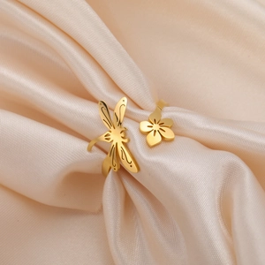 Detailed close-up of golden dragonfly and flower open ring on champagne silk fabric