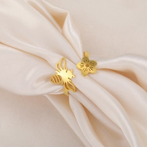 Detailed close-up of a hollow bee and flower open ring on beige satin fabric