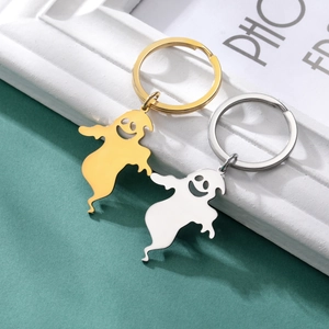 Close-up of polished gold and silver ghost keychains holding hands as a gift set