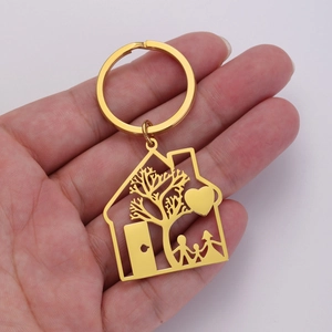 Detailed close-up of a gold house-shaped keychain pendant with family silhouette engraving