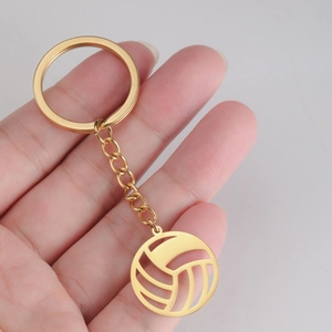 Detail of golden stainless steel volleyball pendant keychain held in hand