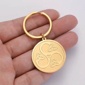 Macro detail of golden stainless steel keychain with engraved Celtic Triskele symbol