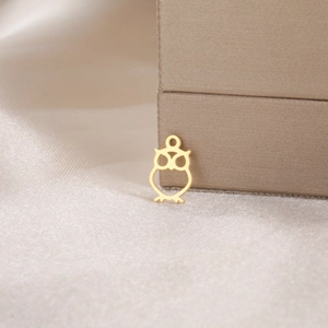 Macro detail of a minimalist gold owl pendant in polished stainless steel for jewelry DIY