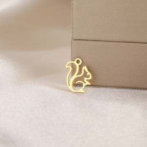 Macro detail of a golden squirrel pendant made of hollowed stainless steel on silk
