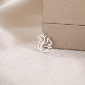 Macro detail of silver squirrel pendant on champagne satin fabric for DIY jewelry