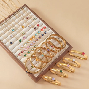 Detail eines vergoldeten Schmucksets mit bunten Herz-Zirkonia auf einem Holztablett