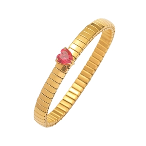 Detailansicht eines goldfarbenen Flexarmbands mit rotem Herz-Edelstein im Schlangendesign