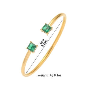 Minimalistische goudkleurige open armband met twee vierkante groene zirkoonstenen