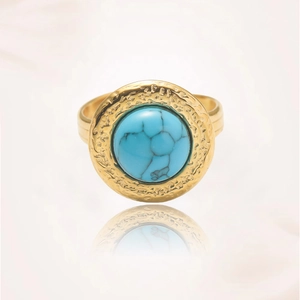 Detalle de anillo dorado vintage con metal martillado y gran piedra turquesa