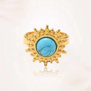 Detalle de anillo dorado con turquesa y diseño de rayos de sol con acabado pulido