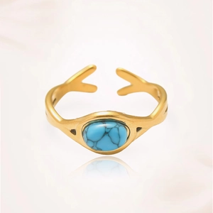 Detalle de un anillo dorado vintage con piedra turquesa óvala y banda de onda única