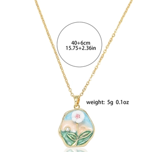 Detail showing freshwater pearl flower pendant with enamel design on gold chain