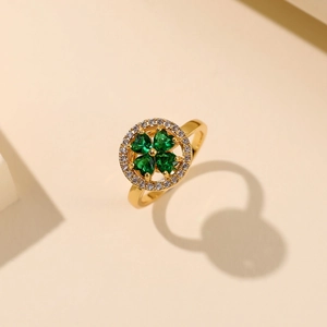Roterende gouden klaverring met groene hartvormige zirkoon en een halo van witte kristallen