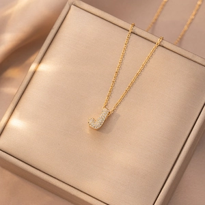 Macro di una collana con ciondolo lettera J dorata con pavé di zirconi cubici