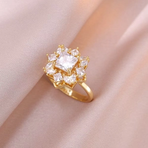 Détail macro d'une bague fleur dorée avec pierres de zircon sur satin champagne