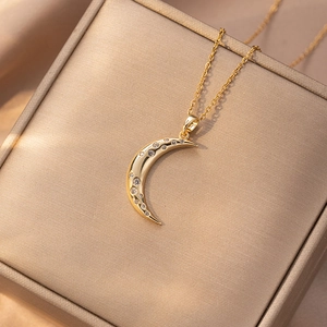 Elegant gold crescent moon pendant necklace with zircons displayed on a luxury jewelry box