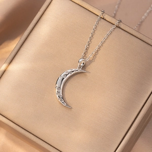 Detailed view of polished silver crescent moon necklace with sparkling zircon stones