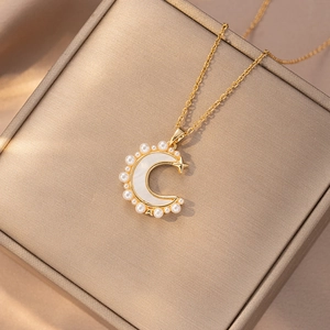 Gold moon and star zircon necklace with pearl inlay on a metallic jewelry box