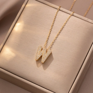 Detailaufnahme einer goldenen Kette mit W-Buchstaben-Anhänger und weißen Zirkonia-Steinen