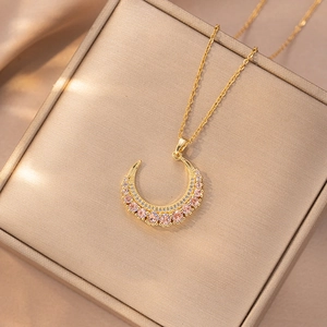 Macro detail of crescent moon pendant with pink and white pavé zircons on gold chain