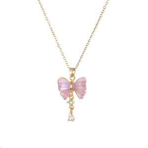 Detail van gouden ketting met roze parelmoeren vlinder en druppelvormige zirkoon hanger