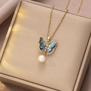 Detailopname van vlinderketting met iriserende schelp en parel op een juwelendoosje