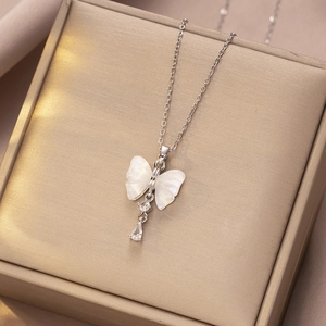 Detail van vlinderketting met witte schelpenvleugels en glinsterende zirkoon kwastjes