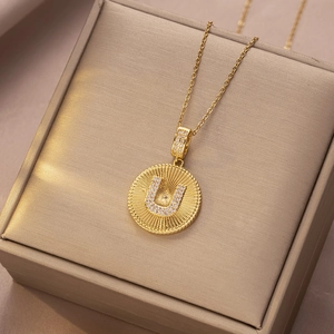 Nahaufnahme des goldenen Buchstaben-U-Anhängers mit Zirkonia und Sonnenstrahltextur
