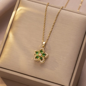 Detailopname van een roterende gouden bloemhanger met groene stenen op een sieradendoos