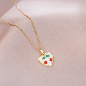 Detail of gold heart pendant with red enamel cherry pattern and polished bead edges