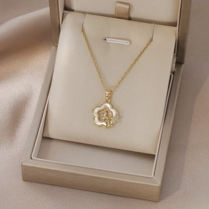 Gros plan d'un pendentif fleur dorée avec nacre et zircons dans un coffret cadeau