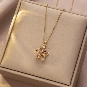 Macro-opname van gouden ketting met paarse bloemenhanger en diamanten op een sieradendoos