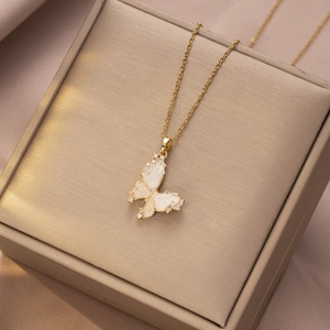 Detailopname van een gouden vlinderhanger met parelmoer vleugels en glanzende zirkonia