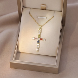Cross necklace with multicolored zircons on gold chain displayed in a jewelry box