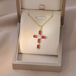 Close-up of golden cross necklace with red stones in a luxury gift box packaging