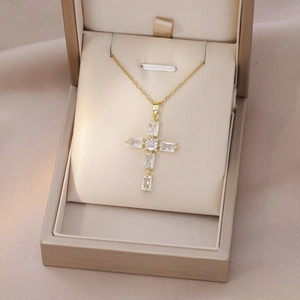 Detail shot of golden cross necklace with emerald cut zircons in a jewelry box