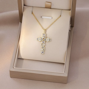 Detailed shot of golden cross necklace with clear zircons in a luxury jewelry box