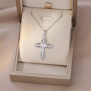 Detailed macro view of silver cross pendant with heart patterns and sparkling zircons