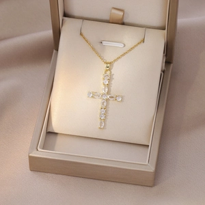 Detailed view of a gold cross pendant necklace featuring sparkling zircon gemstones