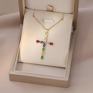 Close-up of gold cross pendant with colorful pear-cut zircon stones in a jewelry box