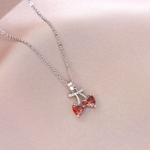 Close-up of cherry pendant necklace featuring red heart stones and crystal leaves